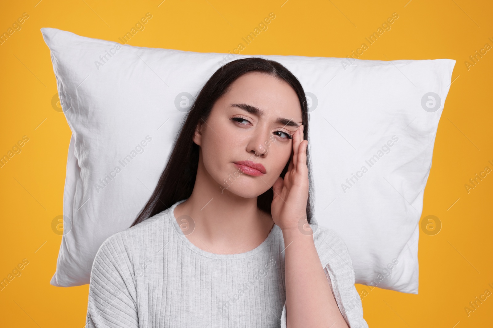 Photo of Tired woman with pillow on yellow background. Insomnia problem