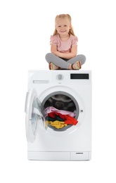 Photo of Cute little girl sitting on washing machine with laundry against white background