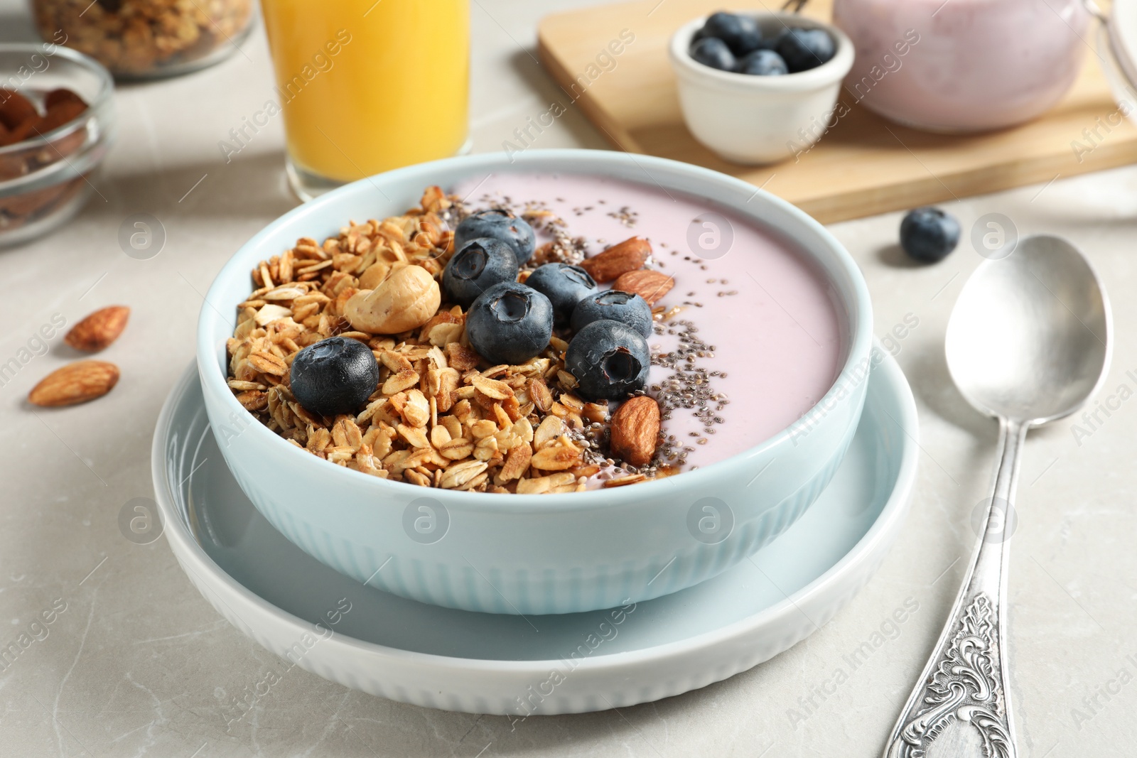 Photo of Bowl of tasty oatmeal with blueberries and yogurt on light grey marble table