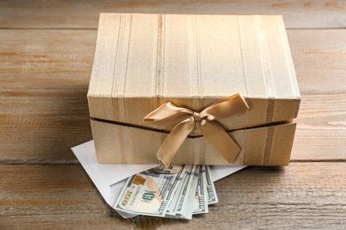 Gift box and dollar bills on wooden table
