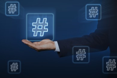 Image of Hashtag concept. Man holding sign on blue background, closeup