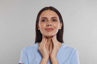 Photo of Endocrine system. Young woman doing thyroid self examination on light grey background