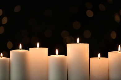 Photo of Burning candles on black background with blurred lights