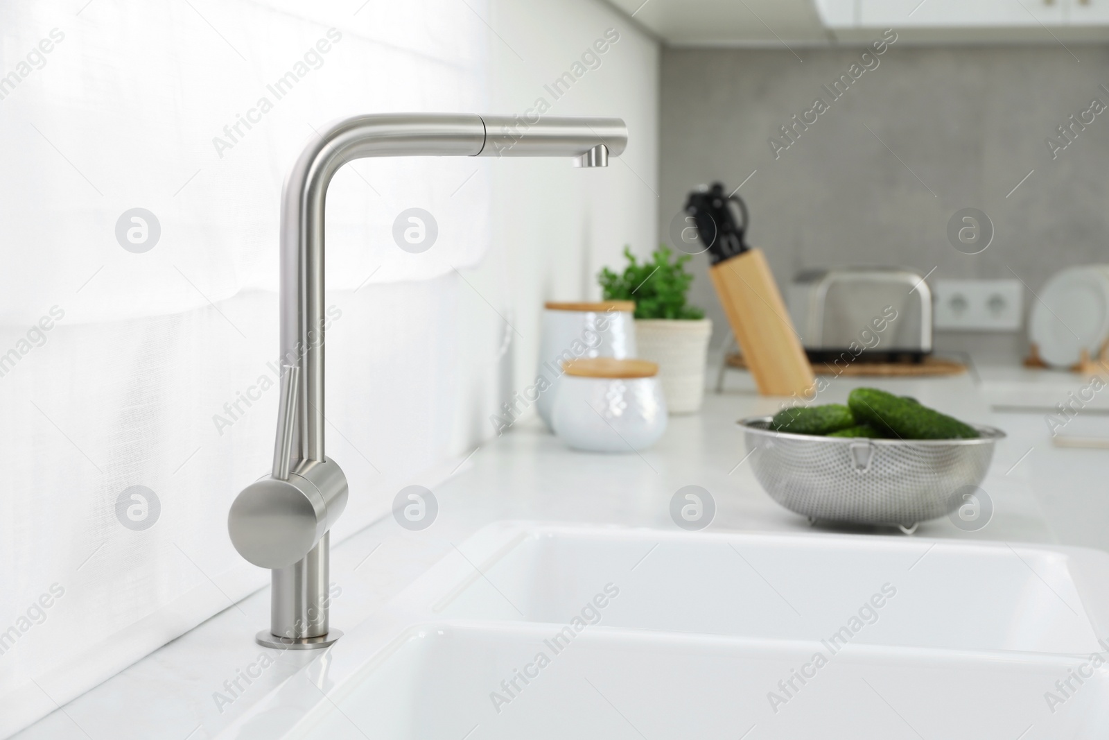 Photo of Modern sink and water tap on kitchen counter. Interior design