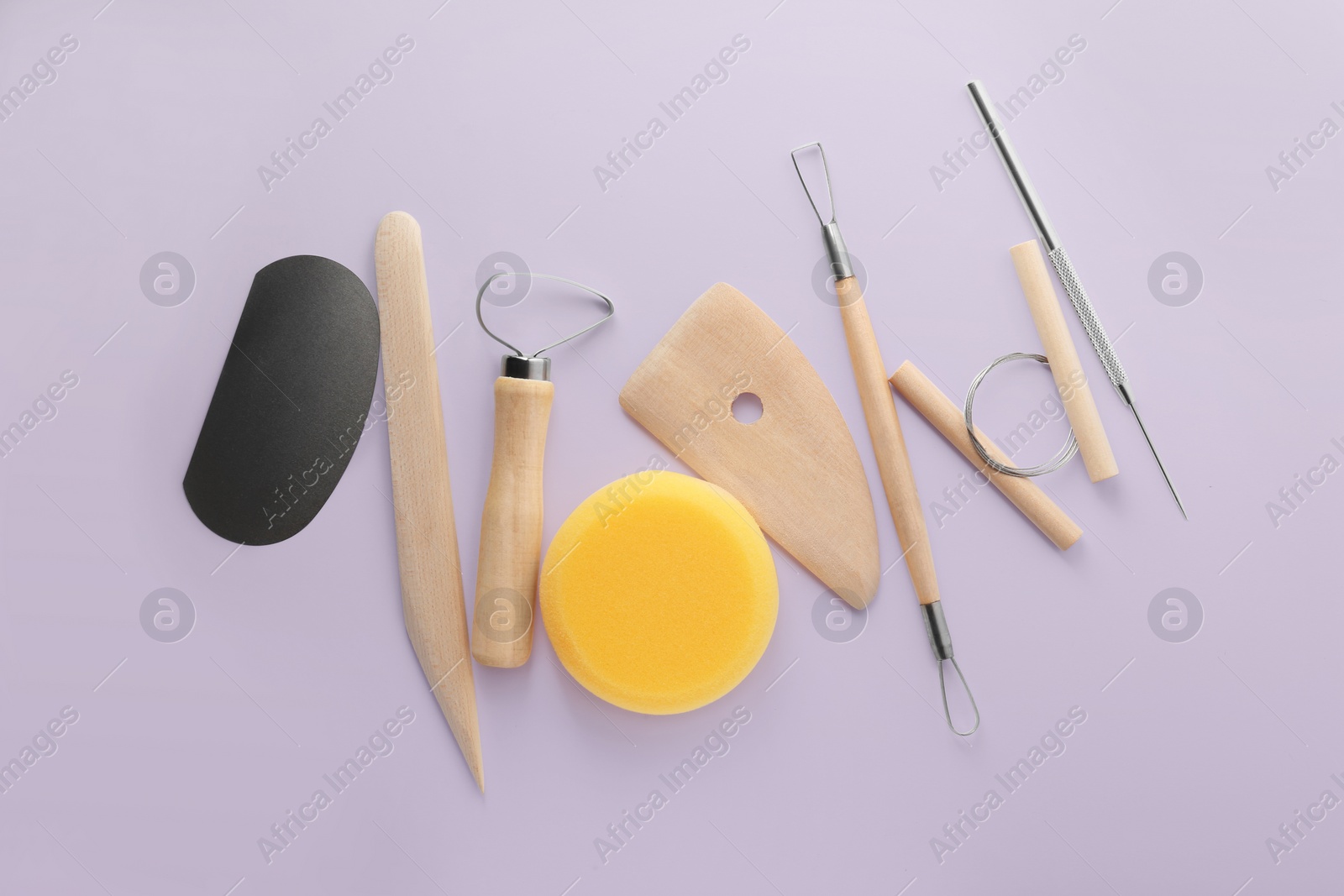 Photo of Set of clay modeling tools on pale violet background, flat lay