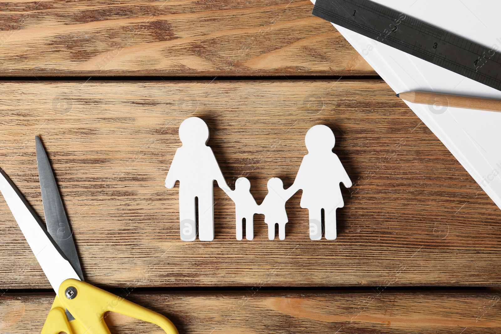 Photo of Flat lay composition with family figure and scissors on wooden background. Life insurance concept