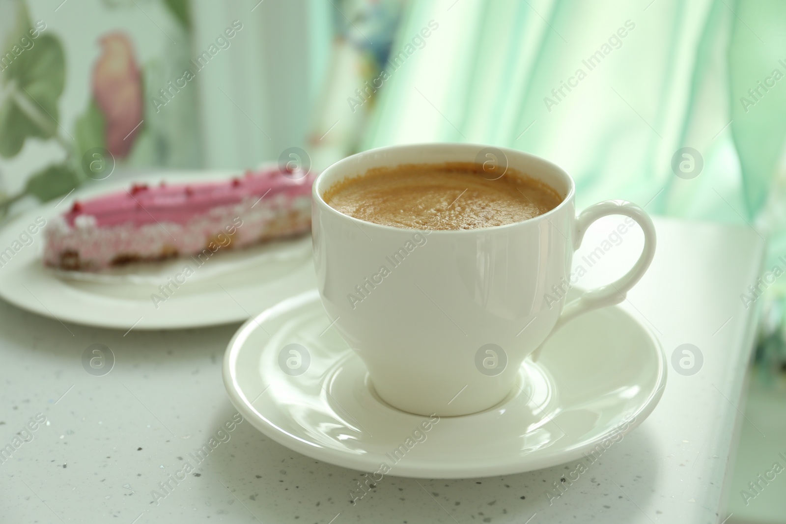 Photo of Cup of delicious aromatic coffee and eclair on white table indoors, closeup