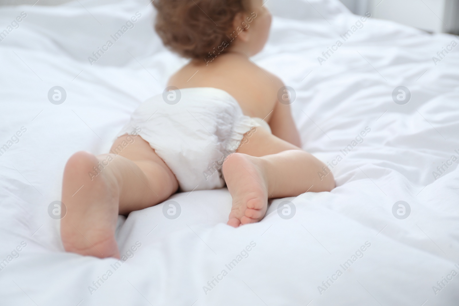 Photo of Cute little baby in diaper on bed