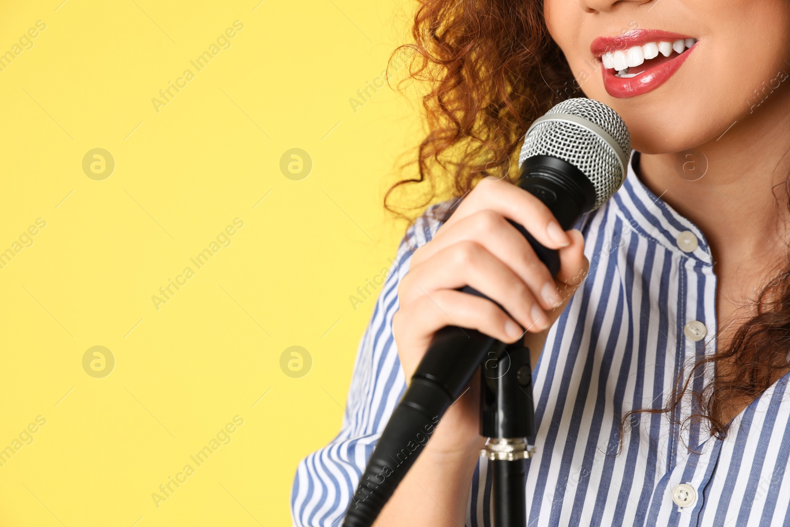 Photo of African-American woman singing in microphone on color background, closeup view with space for text