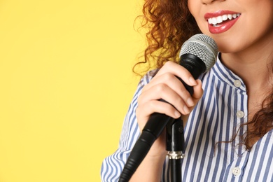 African-American woman singing in microphone on color background, closeup view with space for text