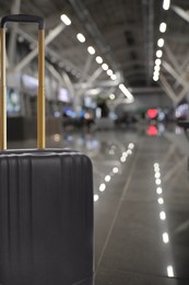 Image of Stylish black suitcase in waiting area at airport terminal