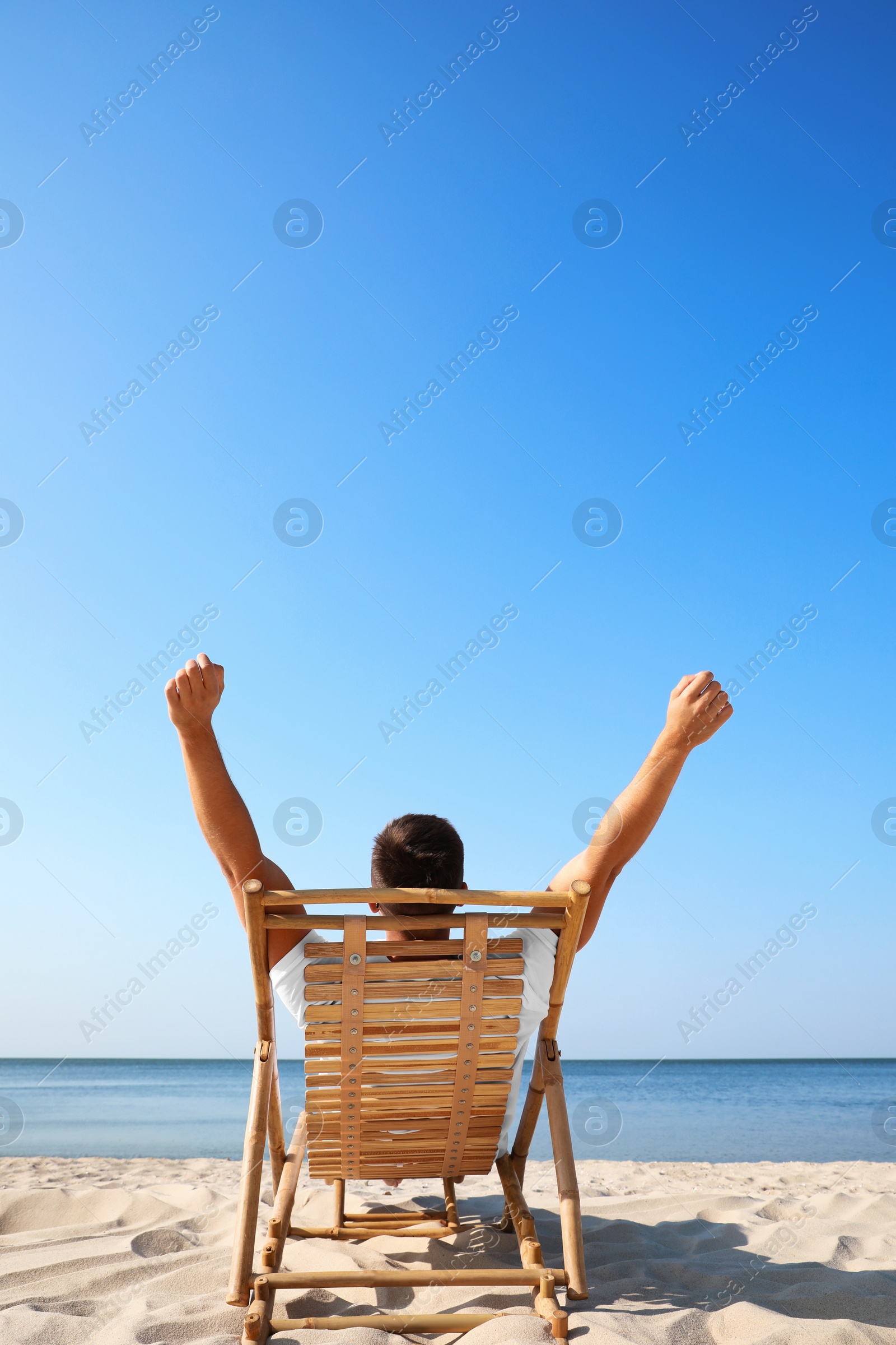 Photo of Young man relaxing in deck chair on sandy beach