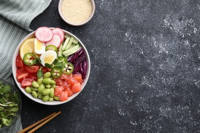Photo of Poke bowl with salmon, edamame beans and vegetables on black table, flat lay. Space for text
