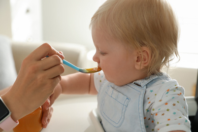 Mother feeding her cute little baby with healthy food at home