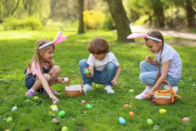 Photo of Easter celebration. Cute little children hunting eggs outdoors