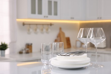 Photo of Set of clean dishware, glasses and cutlery on table in kitchen, space for text