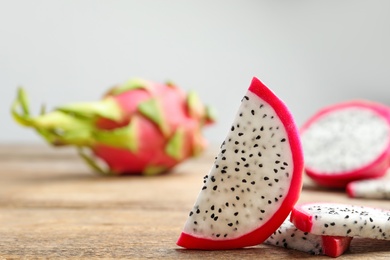 Slices of delicious ripe dragon fruit (pitahaya) on wooden table. Space for text