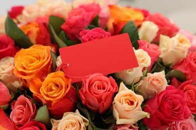 Photo of Bouquet of beautiful roses with blank card, closeup