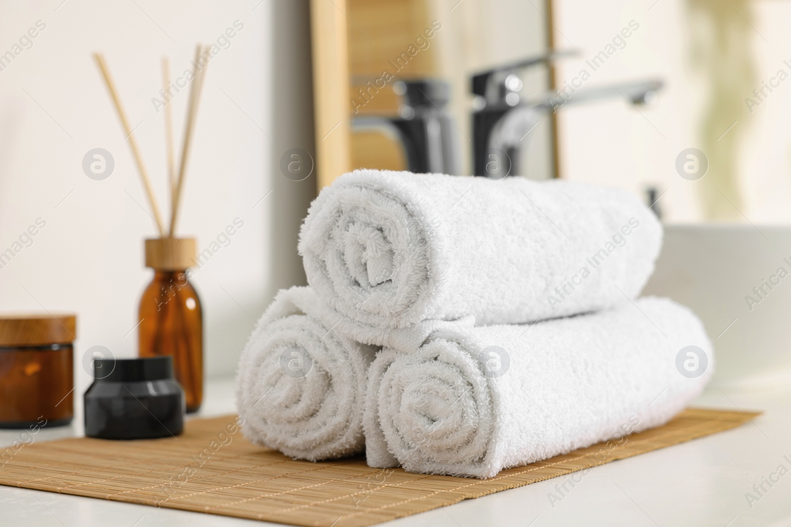 Photo of Rolled soft towels on white table in bathroom