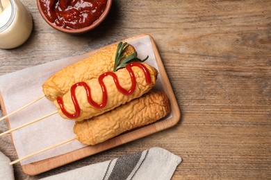 Photo of Delicious corn dogs served on wooden table, flat lay