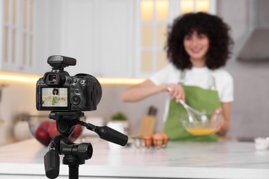 Food blogger recording video in kitchen, focus on camera