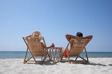 Photo of Couple resting in wooden sunbeds on tropical beach