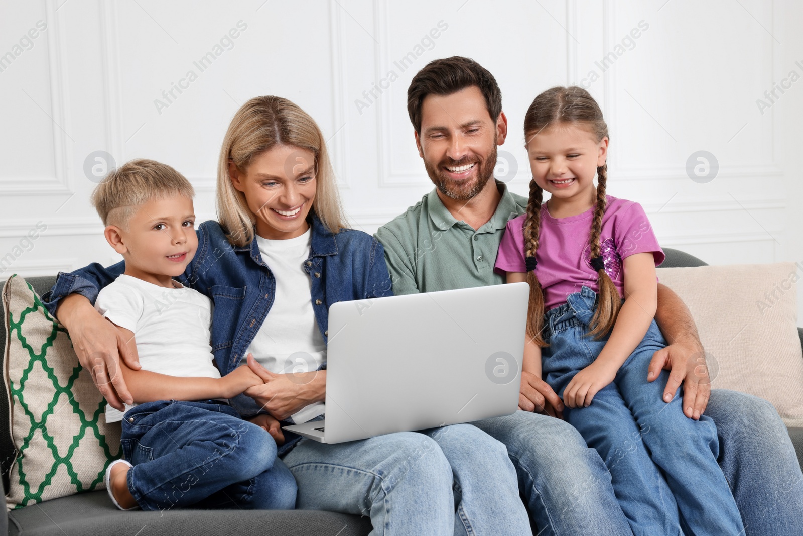 Photo of Happy family with laptop spending time together on sofa at home