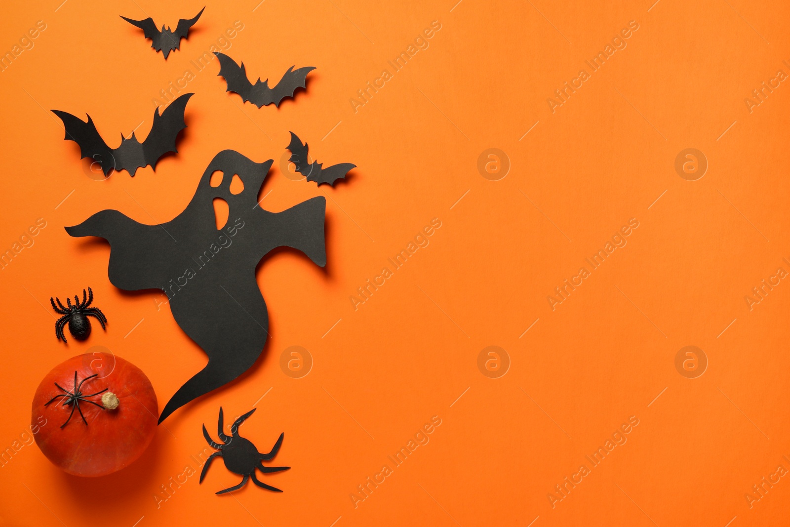 Photo of Flat lay composition with paper ghost, bats and pumpkin on orange background, space for text. Halloween celebration