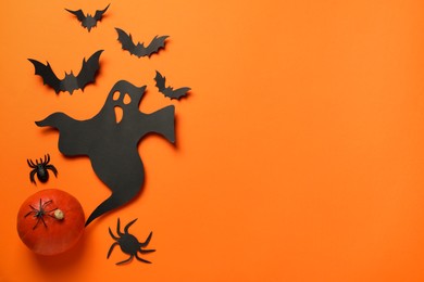 Flat lay composition with paper ghost, bats and pumpkin on orange background, space for text. Halloween celebration