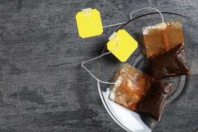 Photo of Saucer with used tea bags on grey table, top view. Space for text