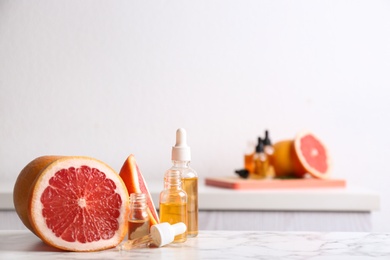 Bottles of essential oil and grapefruit slices on table. Space for text