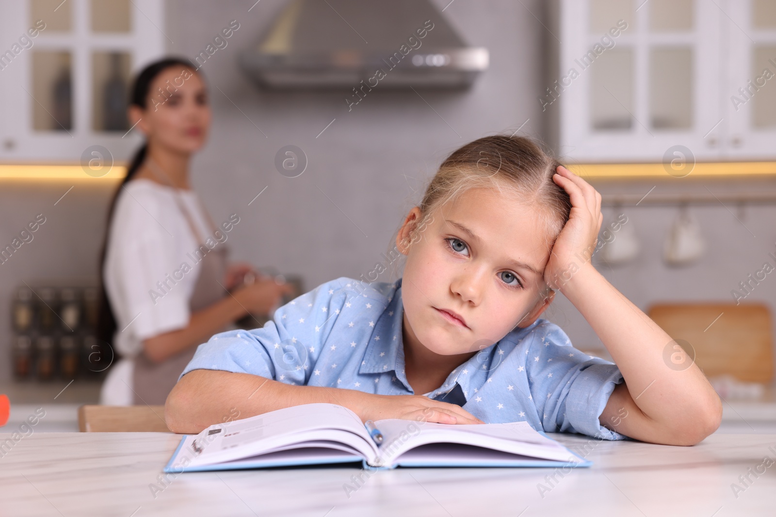 Photo of Mother getting annoyed while daughter doing her homework in kitchen, selective focus. Dyslexia problem