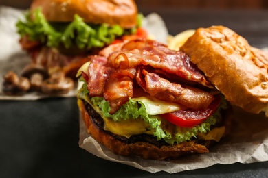 Photo of Delicious burger with bacon on table, closeup