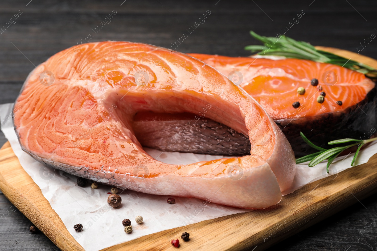 Photo of Fresh salmon steaks with spices on black wooden table