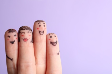 Photo of Four fingers with drawings of happy faces on violet background, space for text