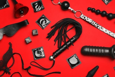 Photo of Different sex toys on red background, flat lay