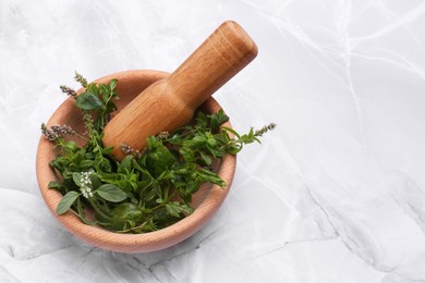 Photo of Mortar with pestle and mint leaves on light grey marble table, space for text