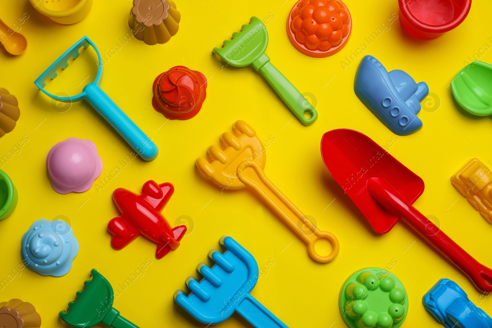 Photo of Beach sand toys on yellow background, flat lay