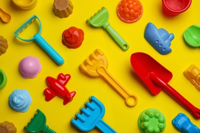 Photo of Beach sand toys on yellow background, flat lay