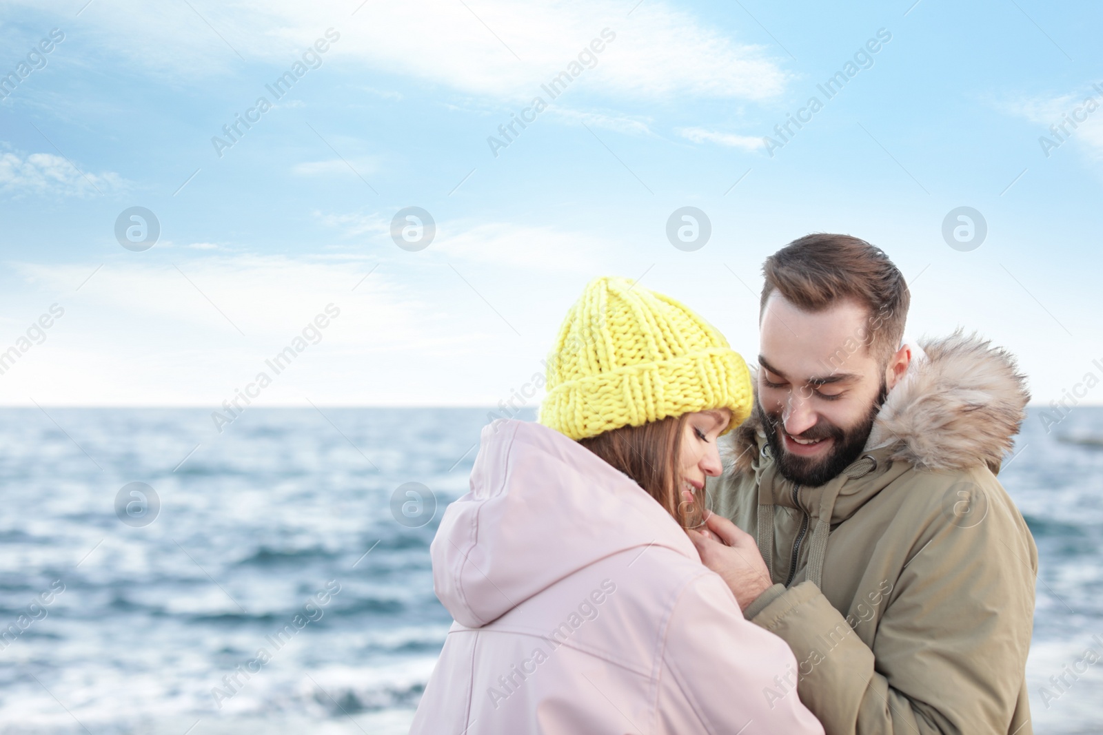 Photo of Lovely young couple holding hands near sea. Space for text