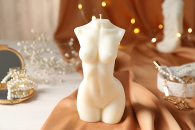 Photo of Composition with beautiful female body shaped candle on white table