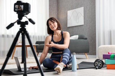 Happy sports blogger recording fitness lesson with camera at home