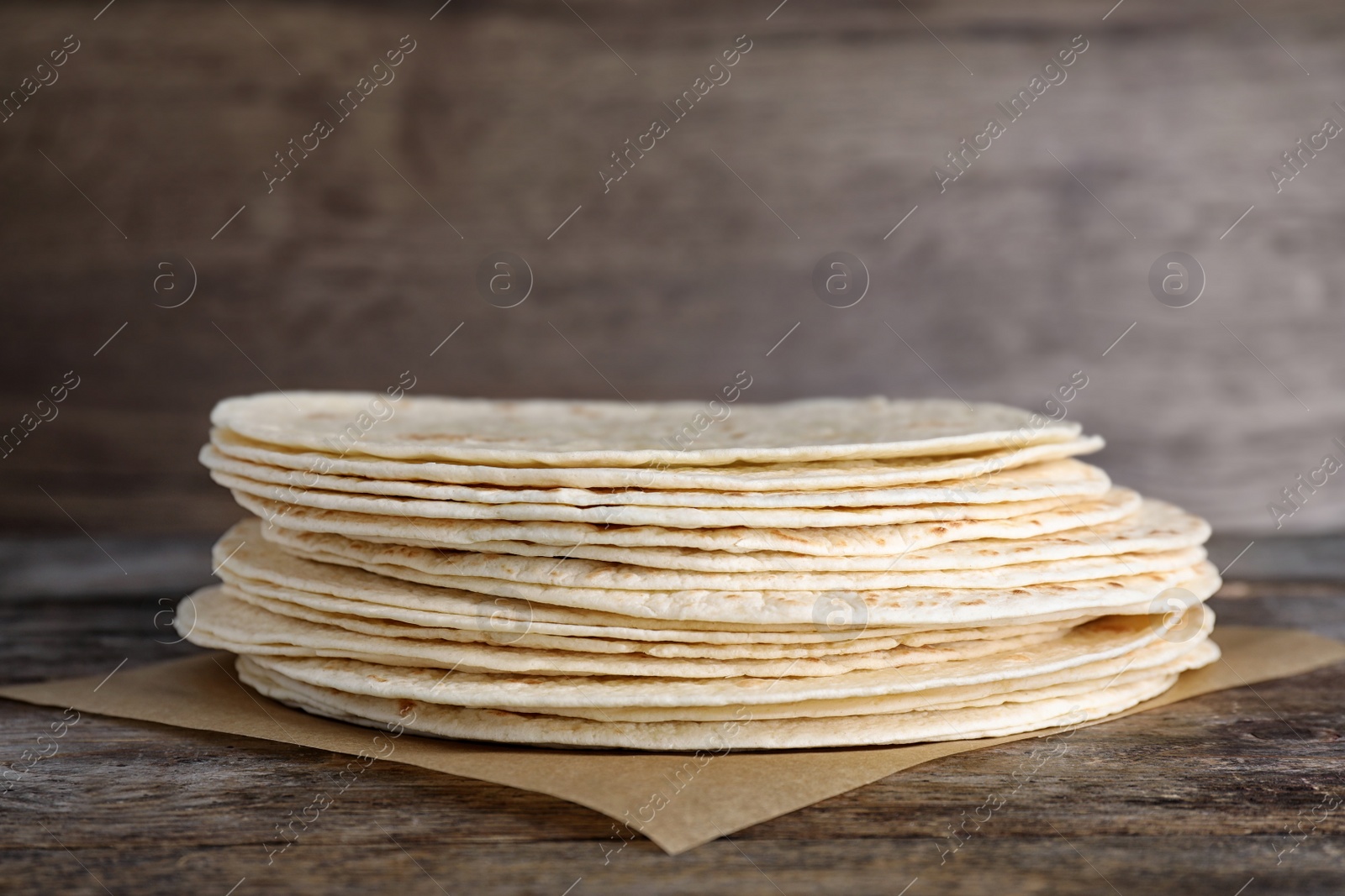 Photo of Stack of corn tortillas on wooden table. Unleavened bread