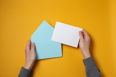 Photo of Woman with blank card at orange table, top view. Space for text