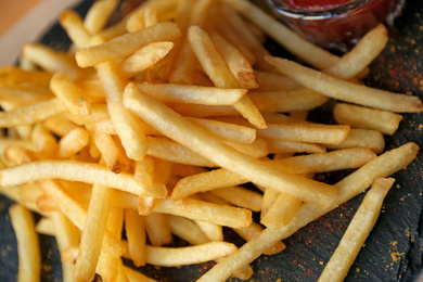 Photo of Tasty French fries with red sauce served on table in cafe, closeup