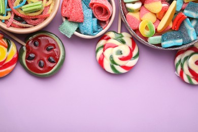 Photo of Many different jelly candies and lollipops on lilac background, flat lay. Space for text