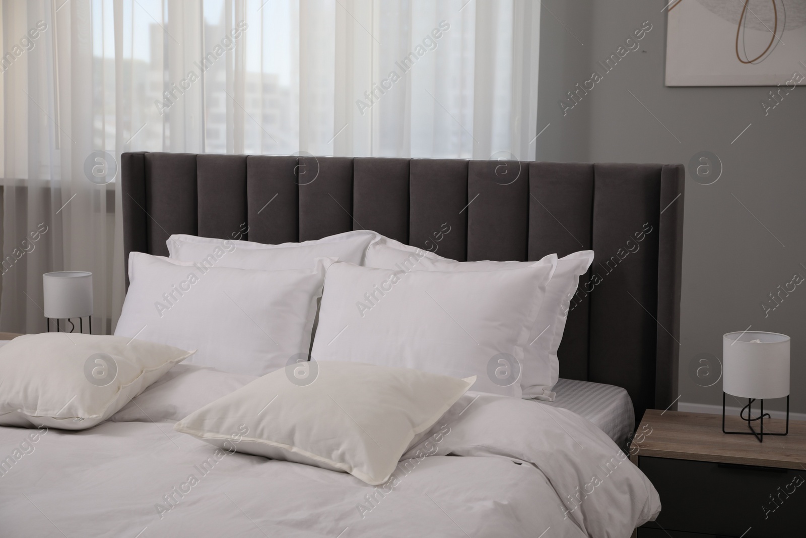 Photo of Many soft white pillows and duvet on bed indoors