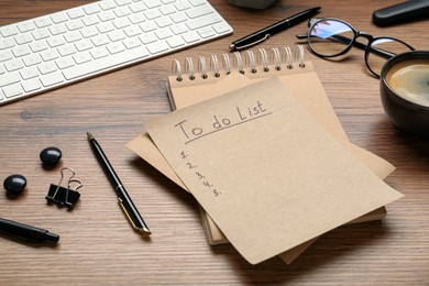 Unfilled To Do list, notebook, pens and cup of coffee on wooden table