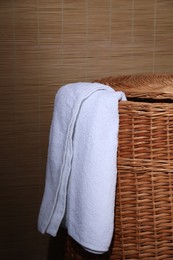 Photo of Soft terry towel on rattan laundry basket indoors