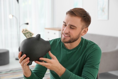 Photo of Young man with piggy bank on blurred background